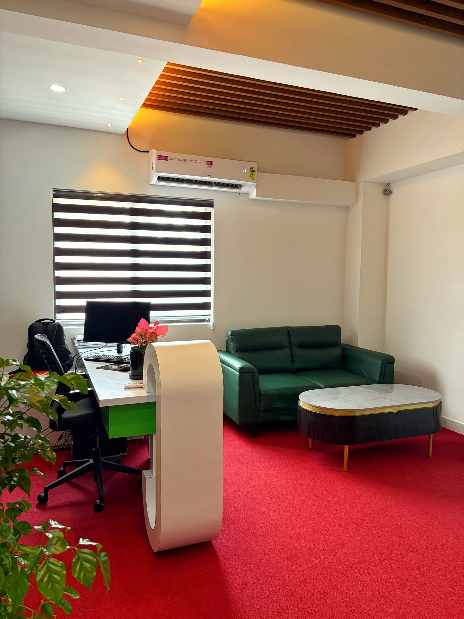 Reception desk with a curved white counter, green sofa and red carpet